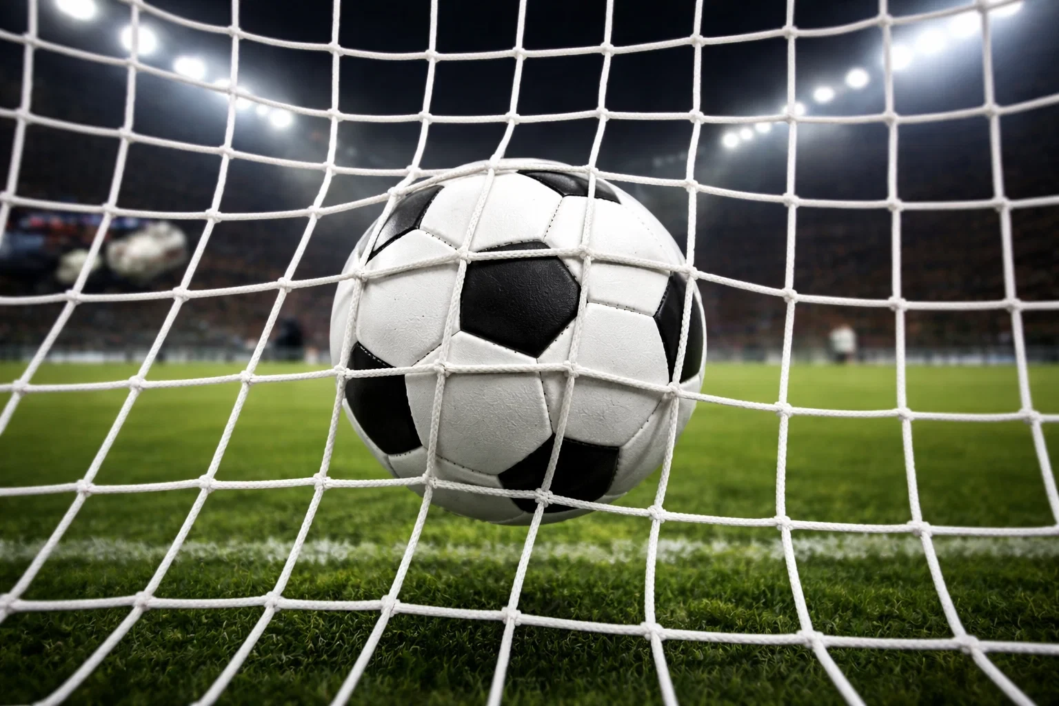 Red de portería de fútbol con balón entrando vista desde dentro